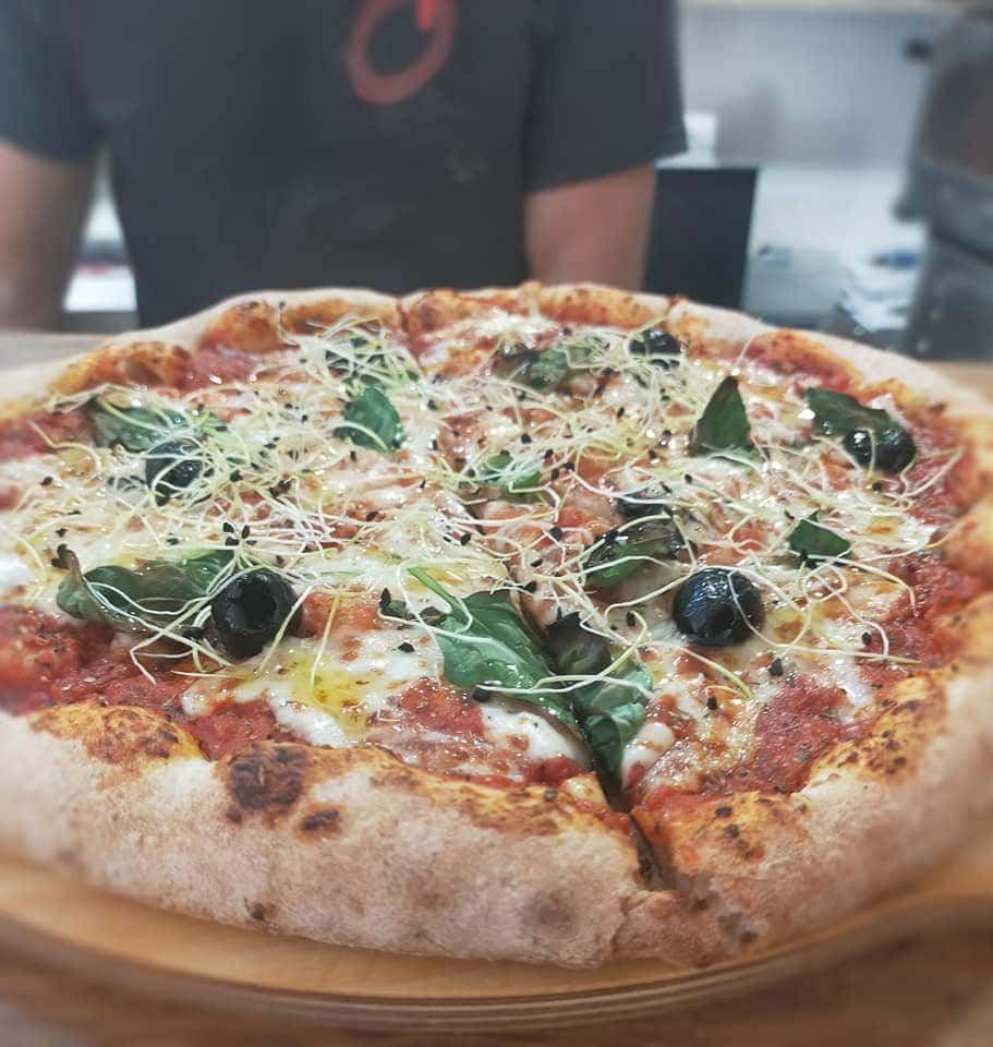 Pizza garnie de roquette et de basilic frais